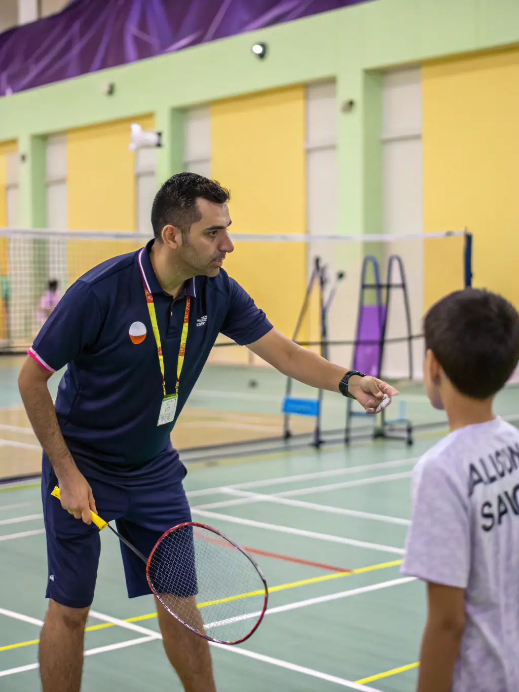 A coach providing personalized badminton training to a club member, demonstrating techniques and offering guidance to enhance their performance at Pornichet Badminton Club.